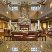 a view of one of the many common areas for senior resident to enjoy each others' company It's spacious, cool, and well-lit, and designed around a large stone fireplace