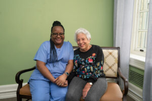 Arnita sits with a resident at The Hearth at Drexel.