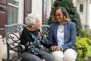 a staff member sits and enjoy a conversation with a resident on our beautiful Bala Cynwyd campus