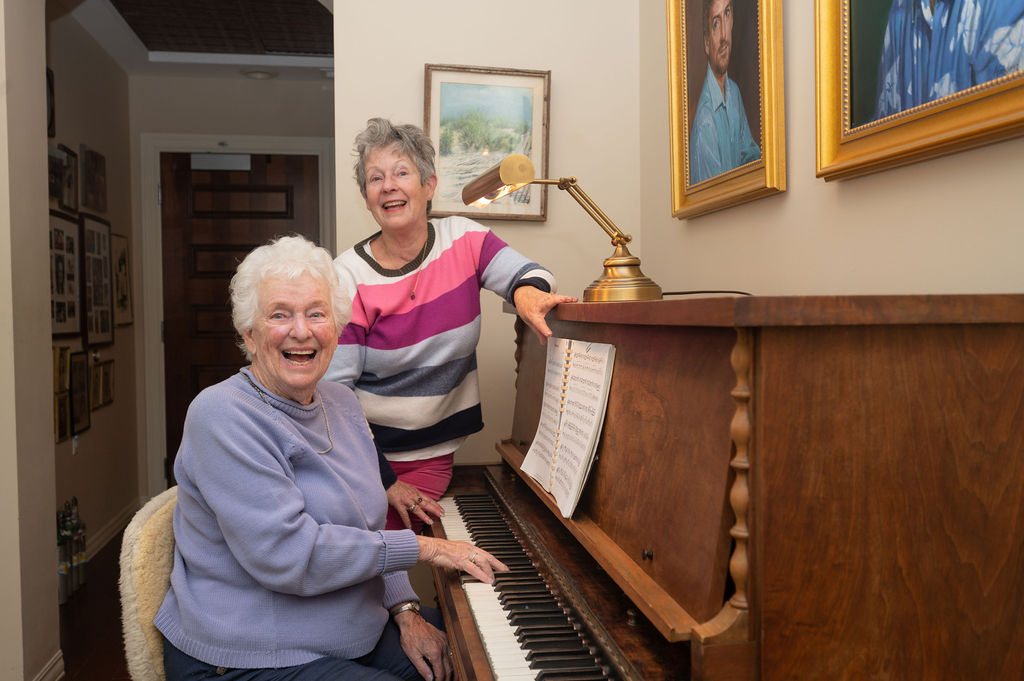 two residents of the Hearth at Drexel enjoy a singalong as one of them plays an upright piano